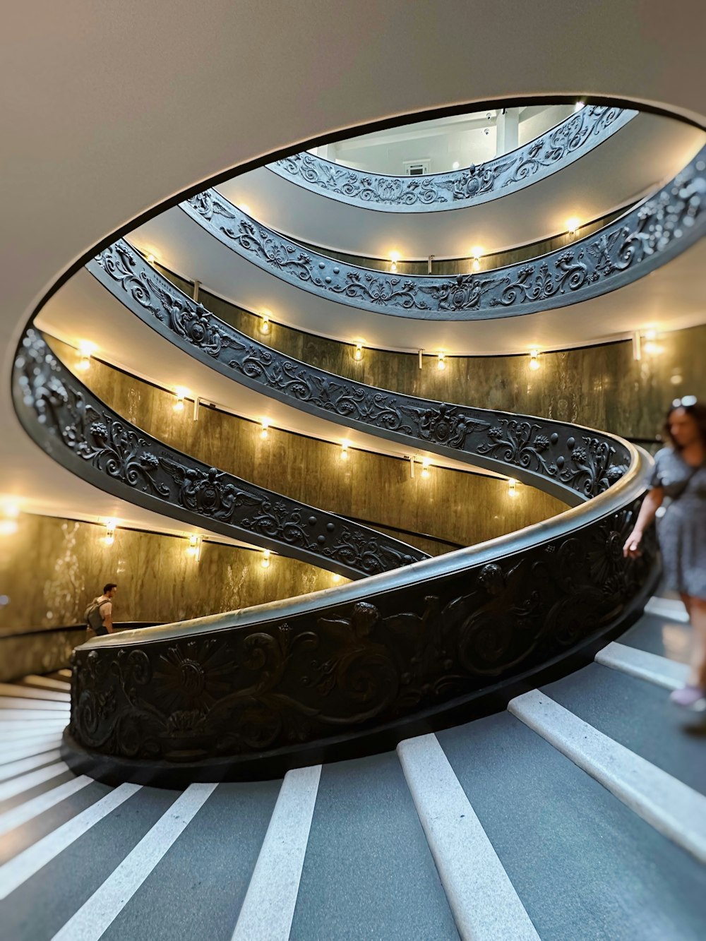a woman is walking down a spiral staircase
