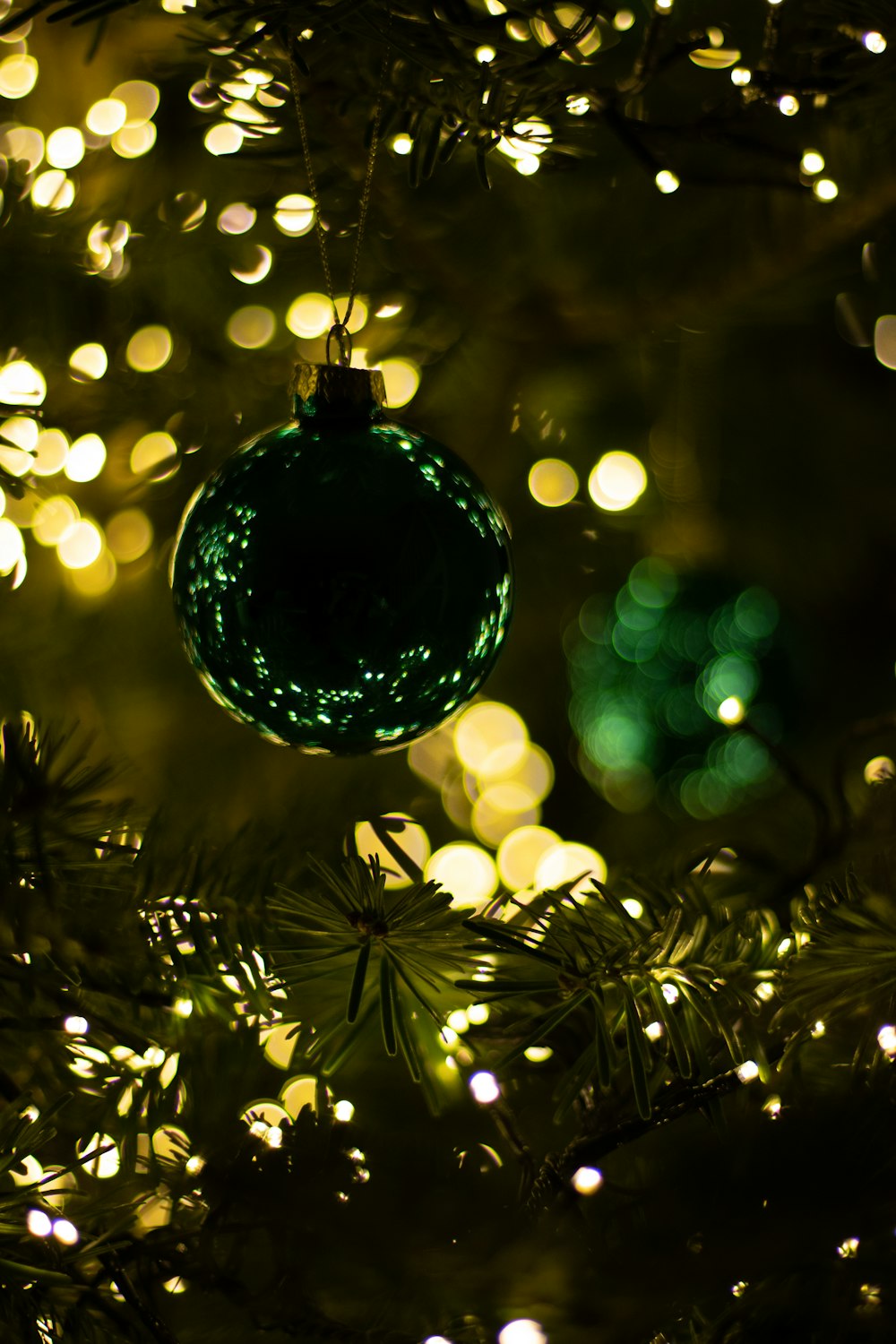 a green ornament hanging from a christmas tree