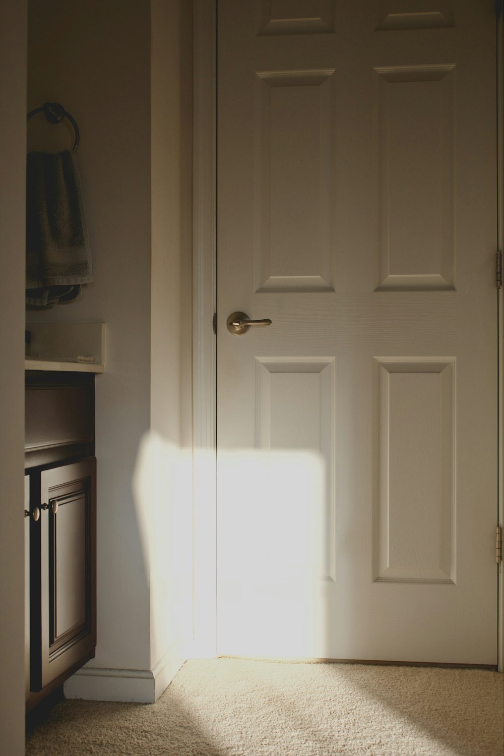 a white door in a room with a light coming through it