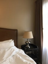 a bed with white sheets and a lamp next to it