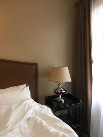 a bed with white sheets and a lamp next to it
