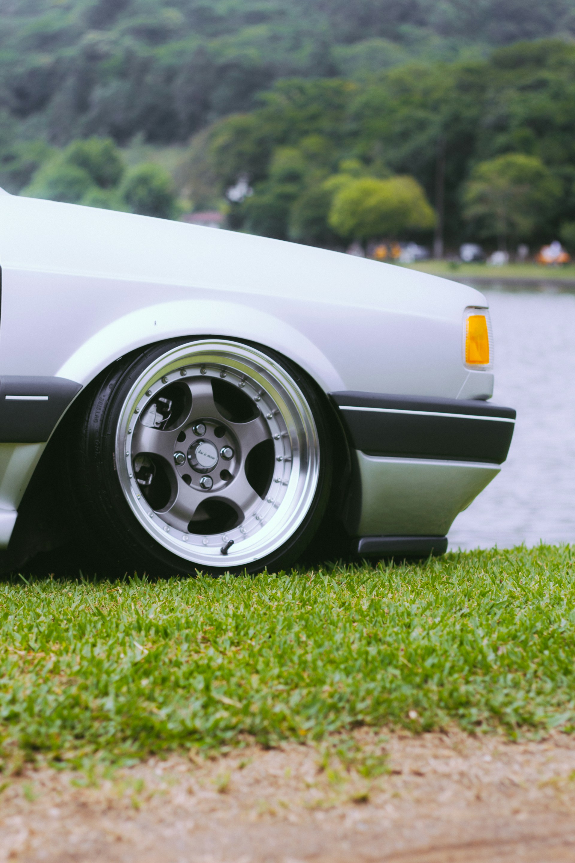 a white car parked on top of a lush green field