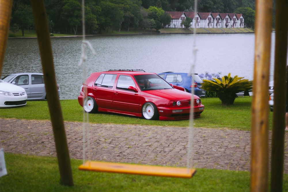 a red car parked in front of a lake