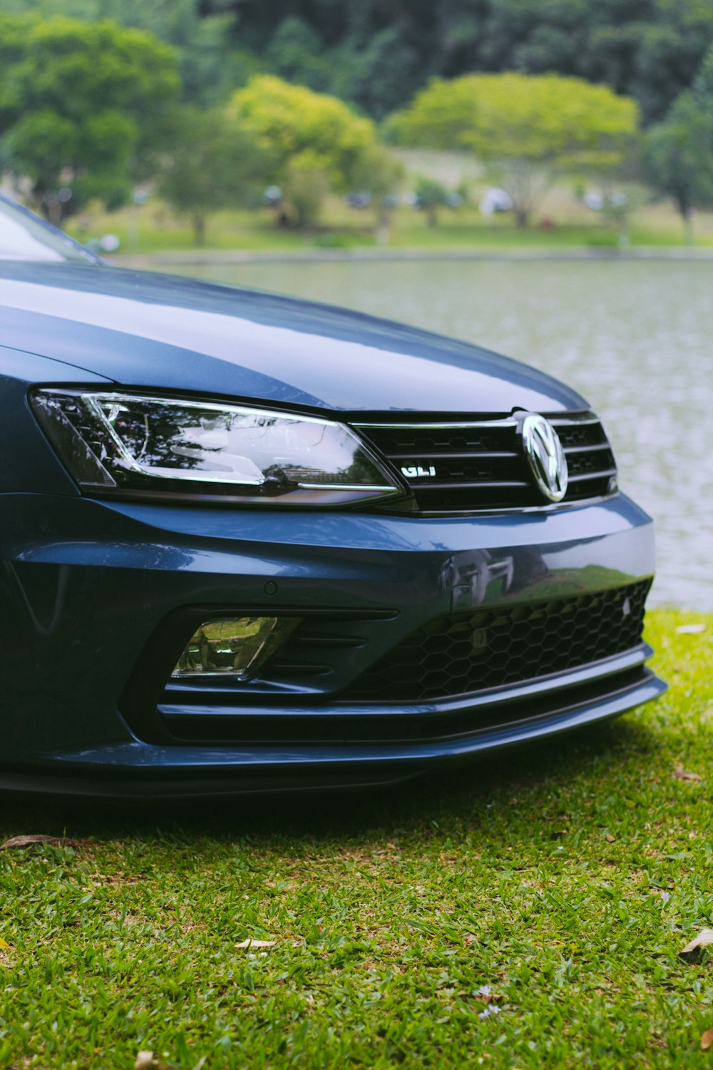 a blue car is parked in front of a body of water