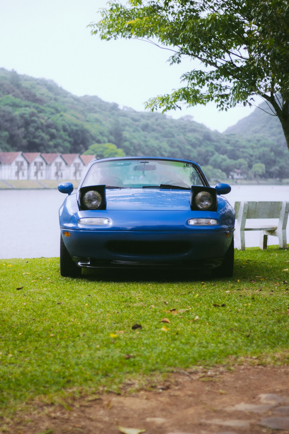 a blue sports car parked next to a lake