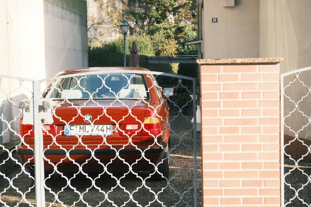 a red car parked behind a chain link fence