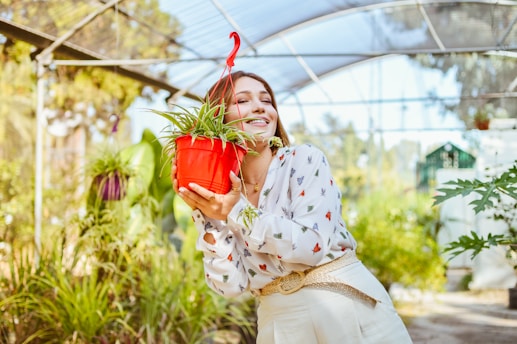 a woman holding a potted plant in a greenhouse