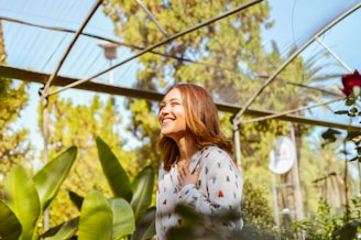 a woman standing in a greenhouse smiling