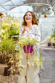 A cheerful florist carefully selecting fresh flowers in a sunlit greenhouse.