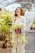 A happy customer holding a shopping bag filled with plants in a bright, sunny park.