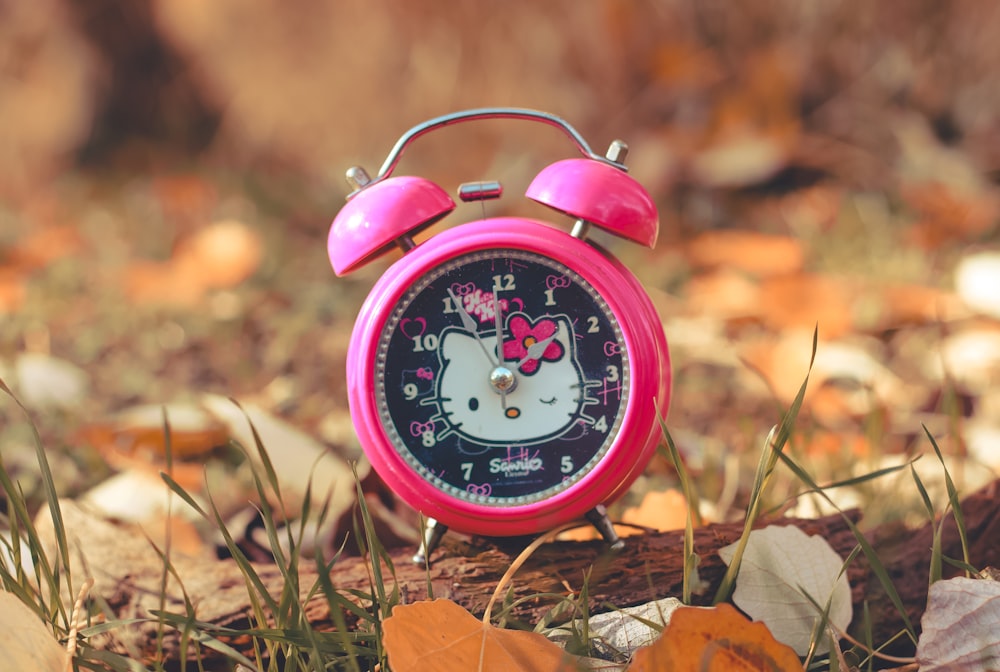 a hello kitty alarm clock sitting in the grass