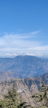 A breathtaking view of a mountain landscape with a clear blue sky and rolling hills in the foreground.
