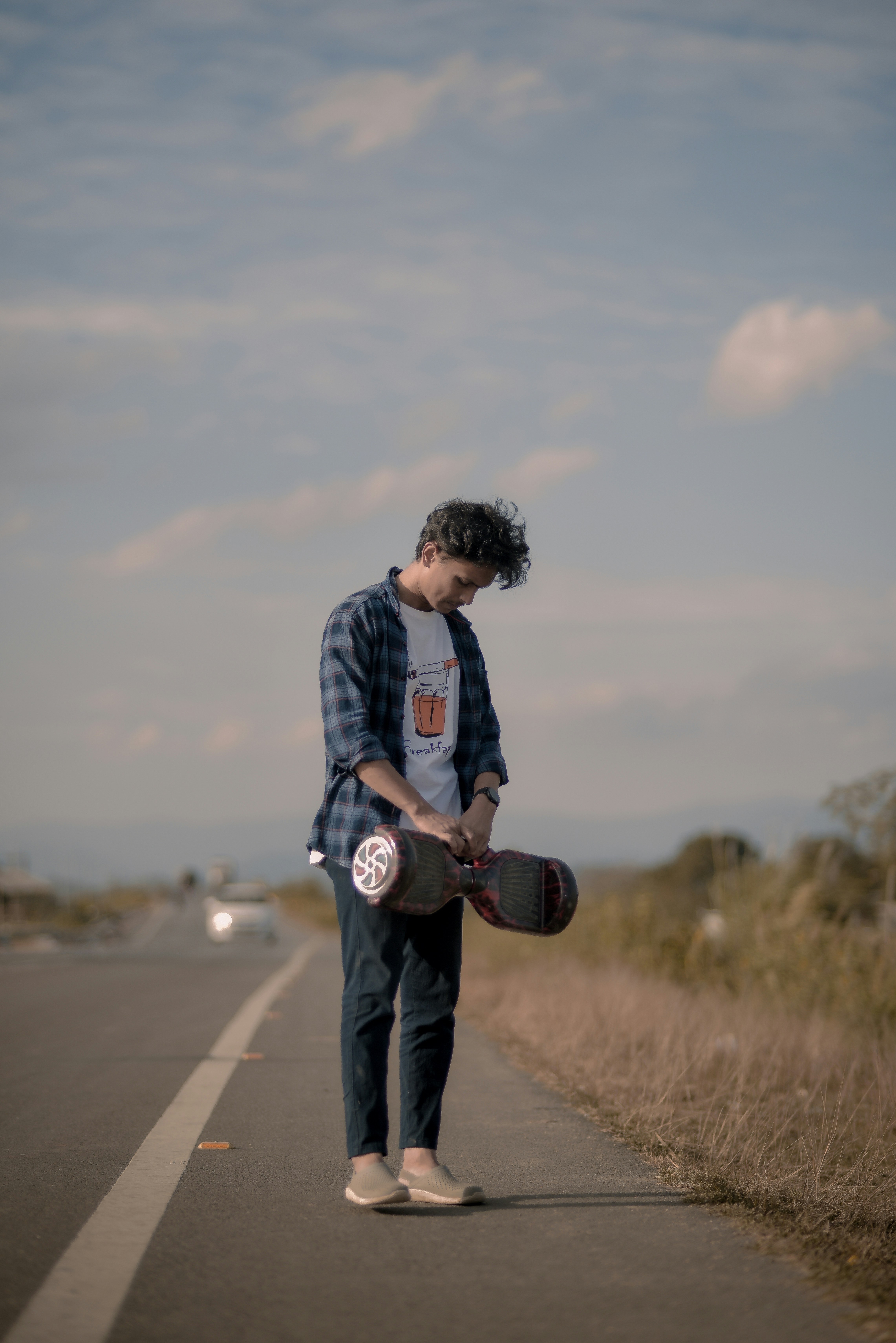 a man holding a skateboard on the side of a road