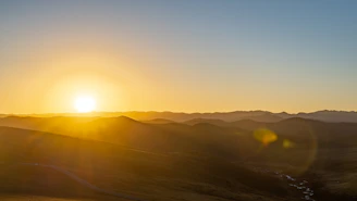 A serene landscape photo capturing golden hour light over rolling hills.