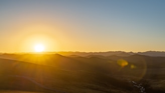 A serene landscape capturing the golden hour light over rolling hills.