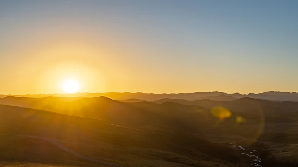 A serene landscape capturing golden light over rolling hills at dusk.