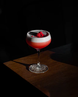 Close-up of a vibrant cocktail with colorful layers and a delicate straw on a sleek black background