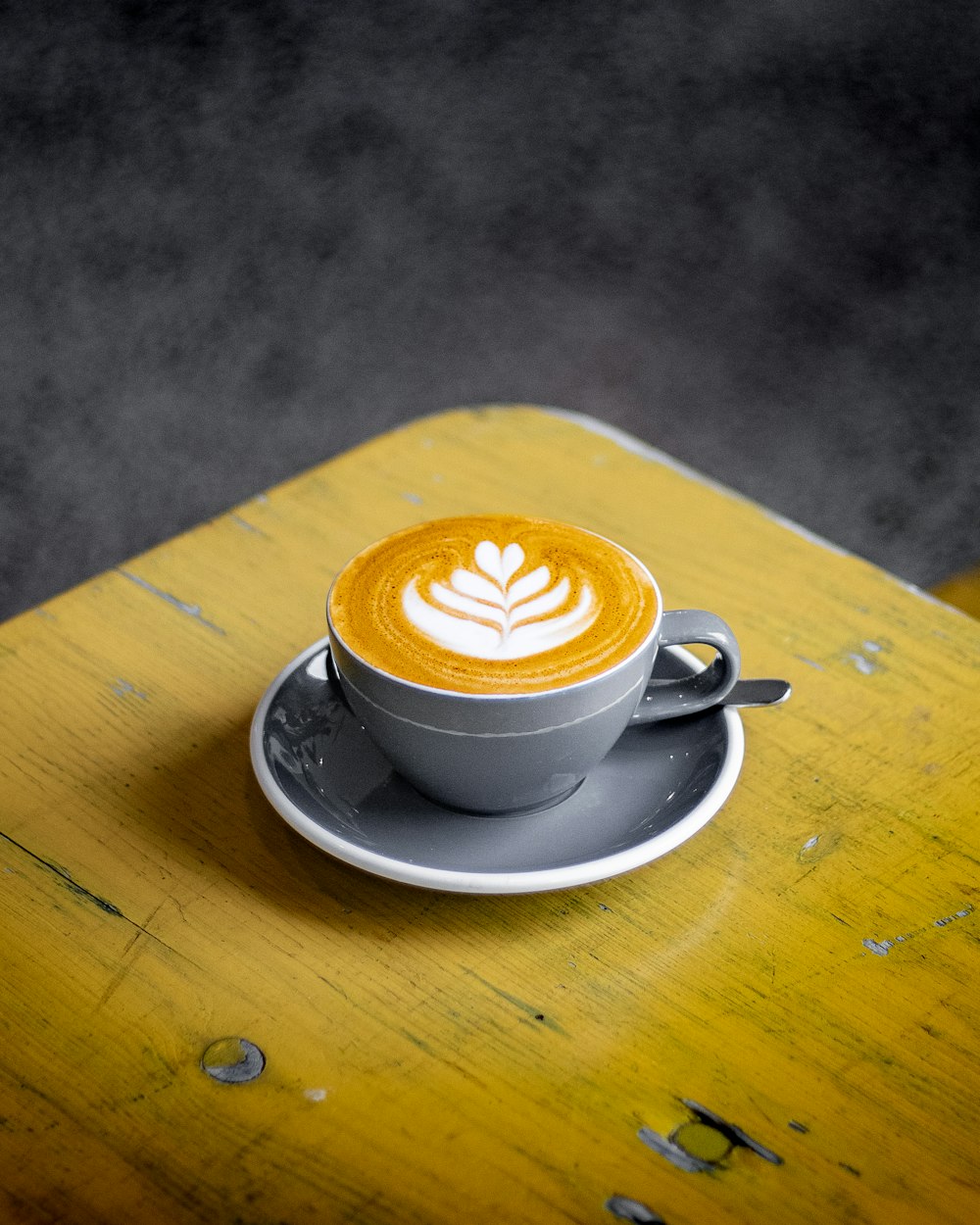 Ein Cappuccino auf einer Untertasse auf einem gelben Tisch