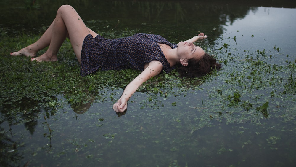 a woman laying on the ground in the water