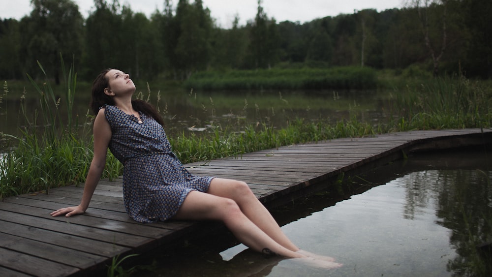 a woman sitting on a dock in a dress