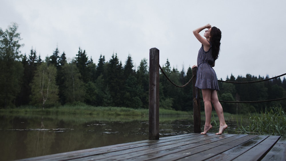 a woman standing on a dock next to a body of water