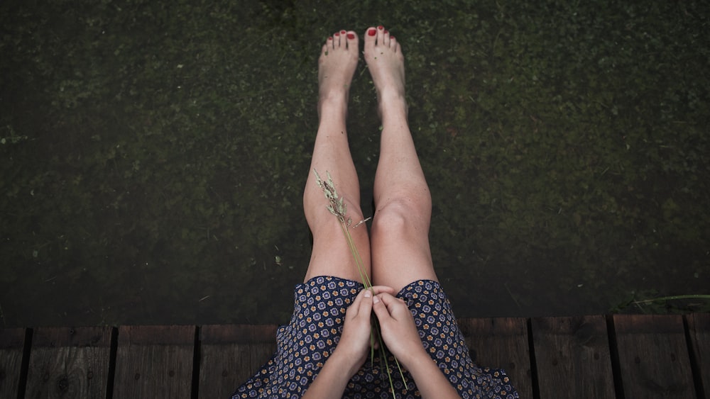 a woman with her legs crossed sitting on a dock