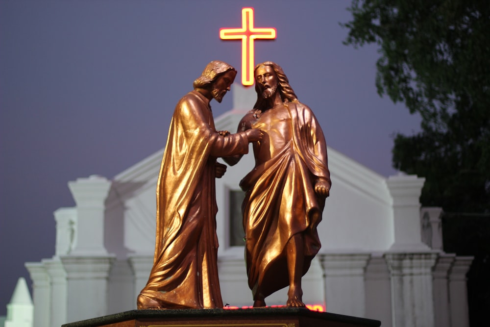 a statue of two people holding hands in front of a cross