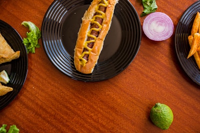 Close-up of a golden, crispy corn dog with a variety of dipping sauces on a rustic wooden table.