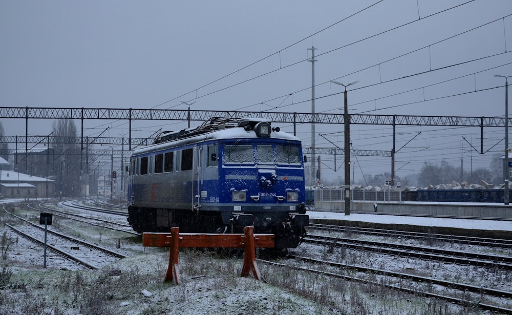 a blue and silver train traveling down train tracks