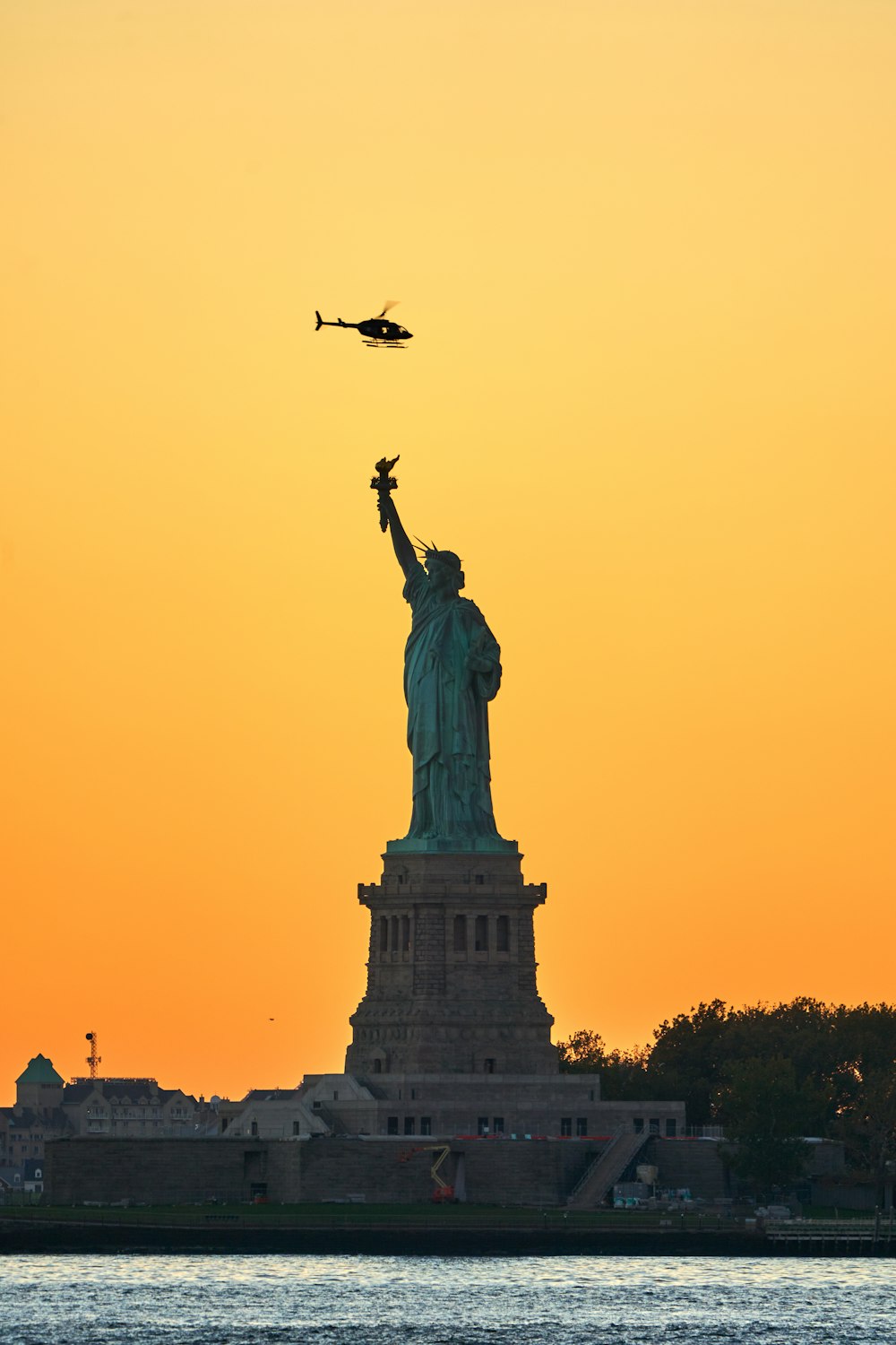 Ein Flugzeug fliegt bei Sonnenuntergang über die Freiheitsstatue
