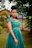 Elegant woman in a floral dress from twelve28, posing outdoors with greenery in the background.
