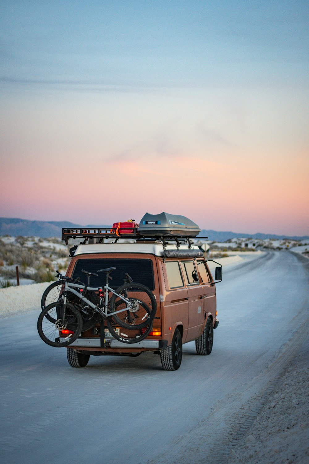 a van driving down a road with a bike on top of it