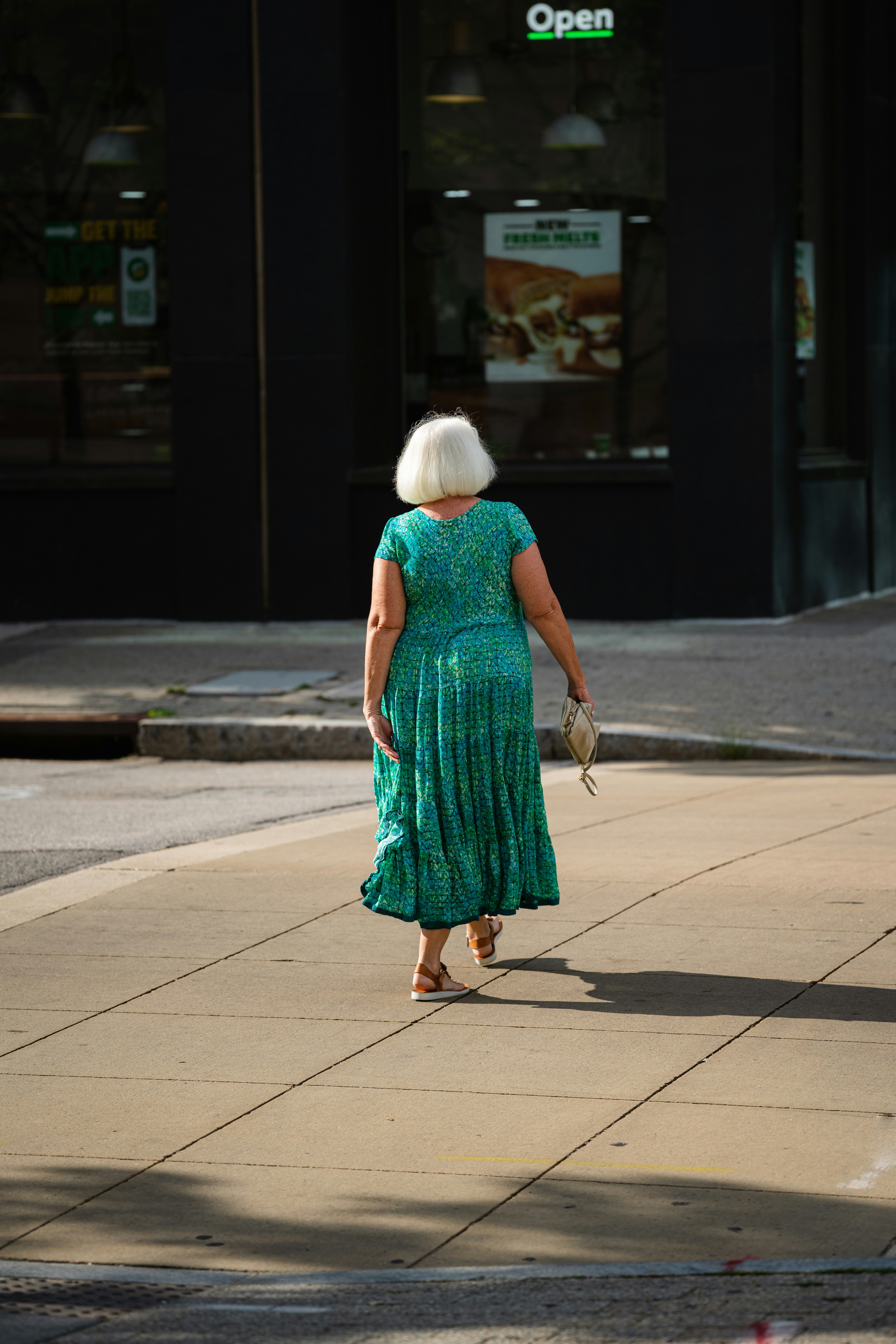 a woman in a green dress walking down the street