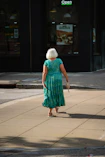 a woman in a green dress walking down the street