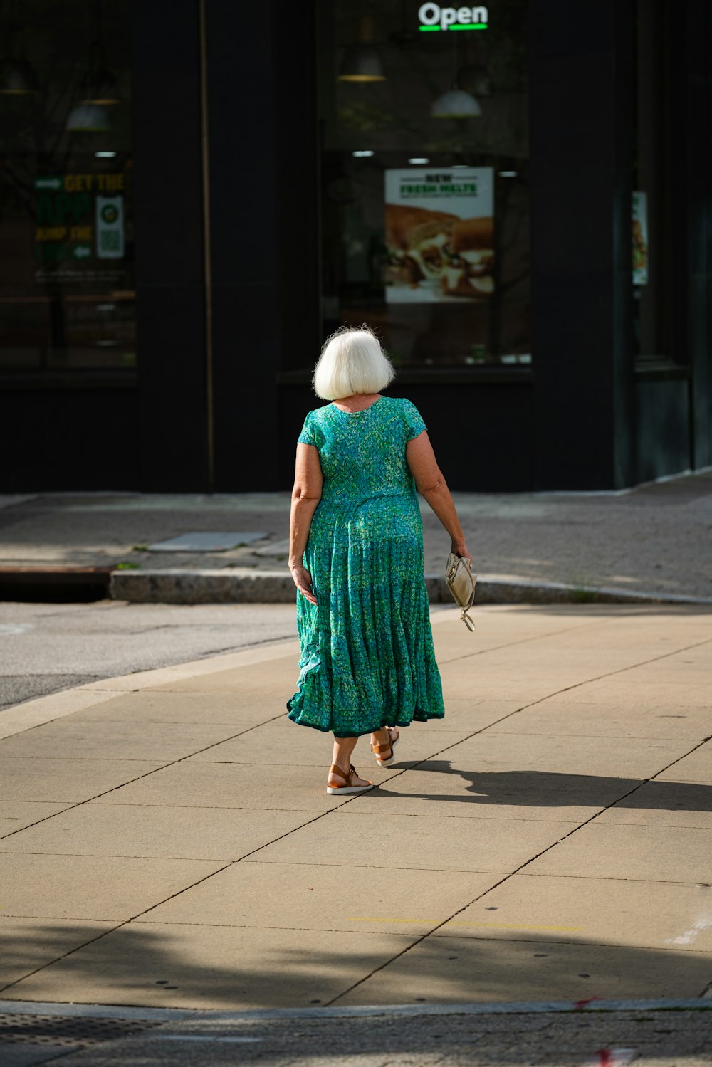 Eine Frau in einem grünen Kleid geht die Straße entlang