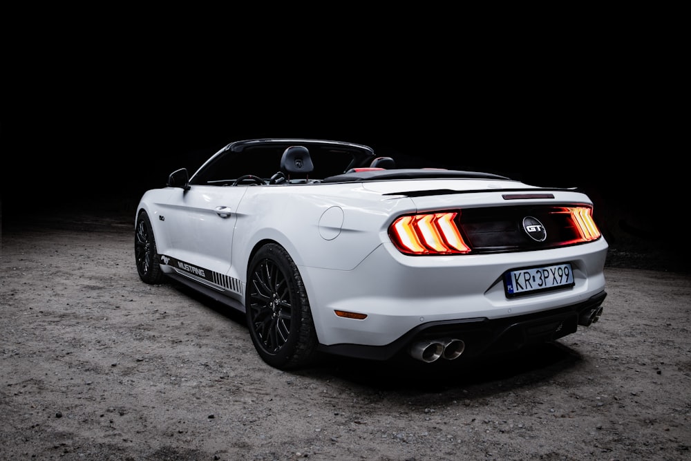 a white mustang convertible parked in the dark