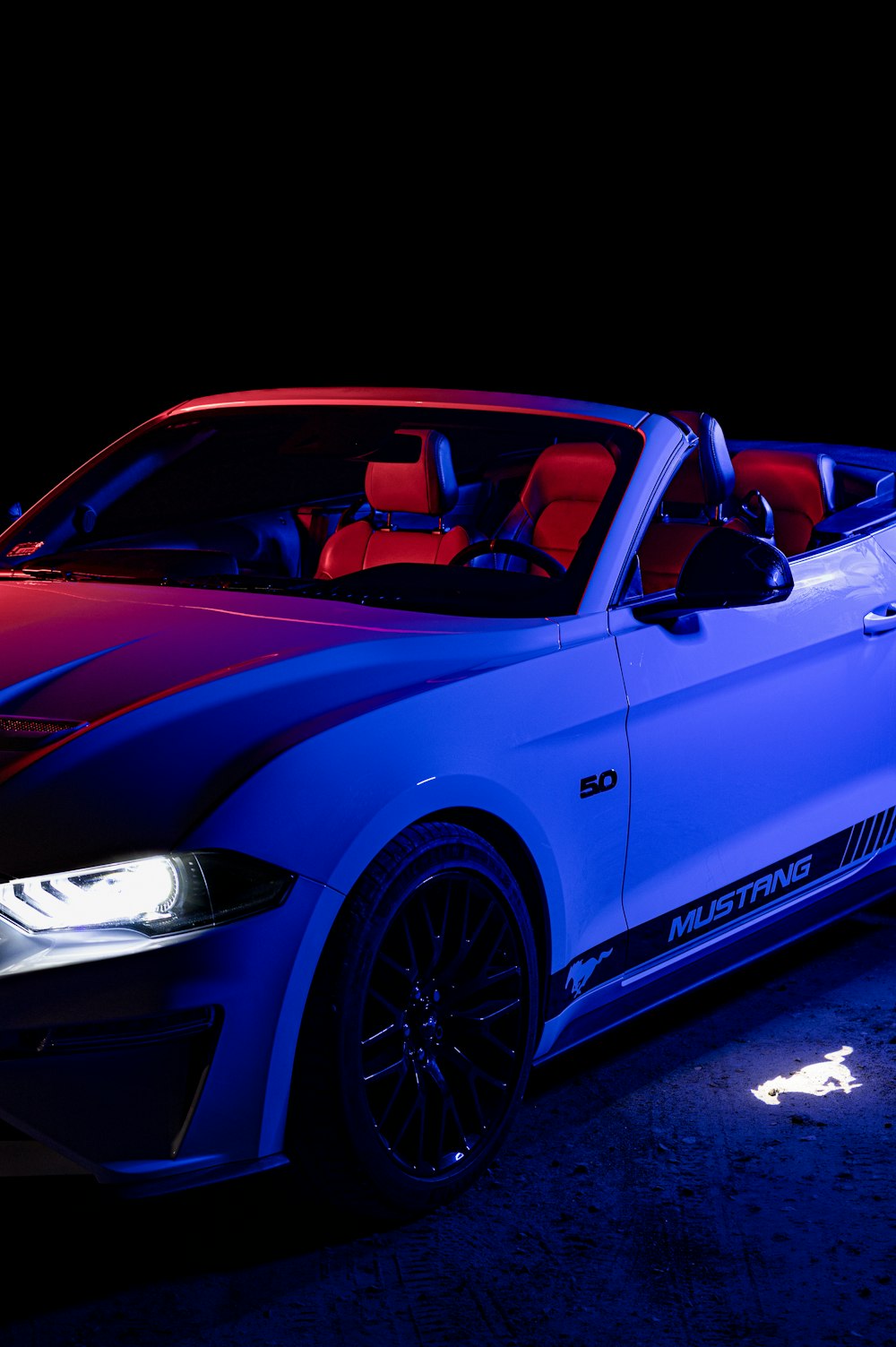 a red and blue convertible car parked in the dark