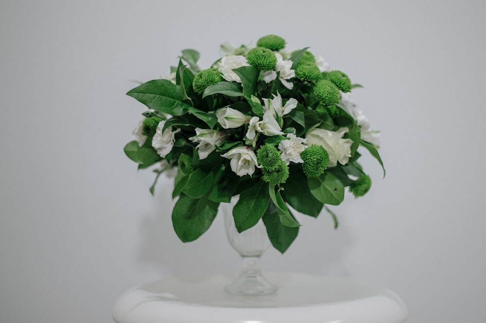 eine Vase gefüllt mit weißen und grünen Blumen