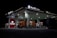 A gas station brightly lit at night with a large truck parked at the fuel pumps. The architecture is modern with a flat roof and multiple fuel dispensers. The signage at the top and on the building includes both Chinese characters and English letters. The station is relatively quiet and appears to be well-maintained, with the focus on the truck and the illuminated stations.