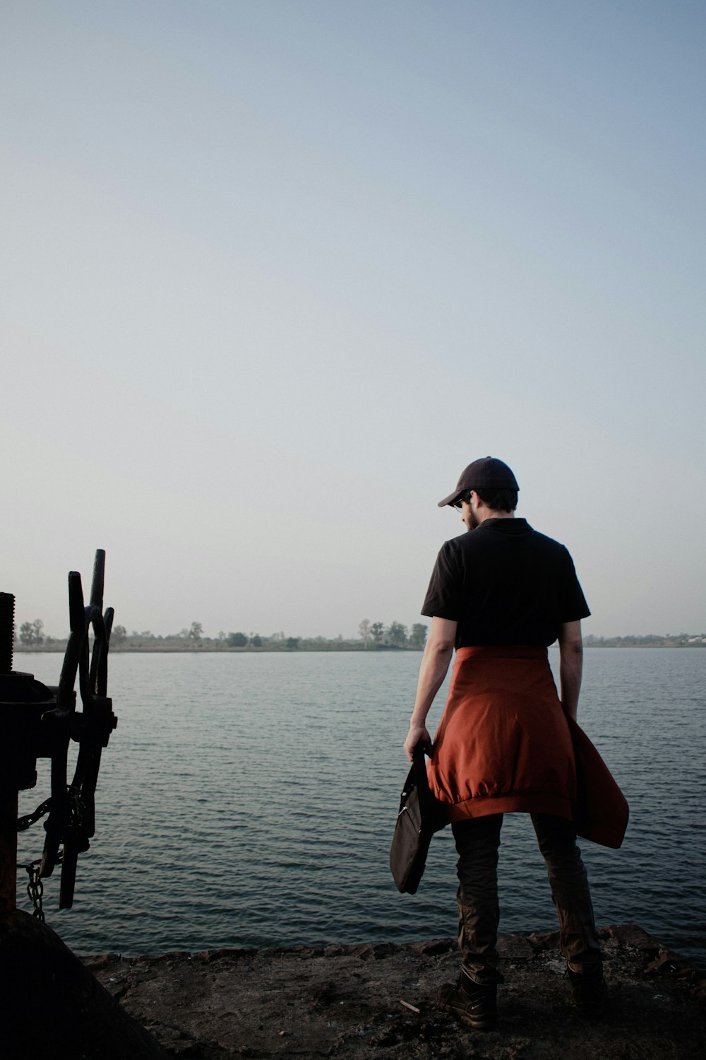 a man standing on a dock next to a body of water