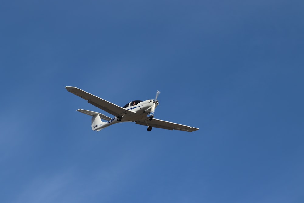 a small airplane flying through a blue sky