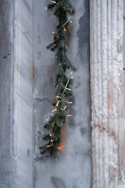 A clean, elegant photograph of a luxury garland draped over a minimalist white mantelpiece, highlighting natural textures and soft lighting.