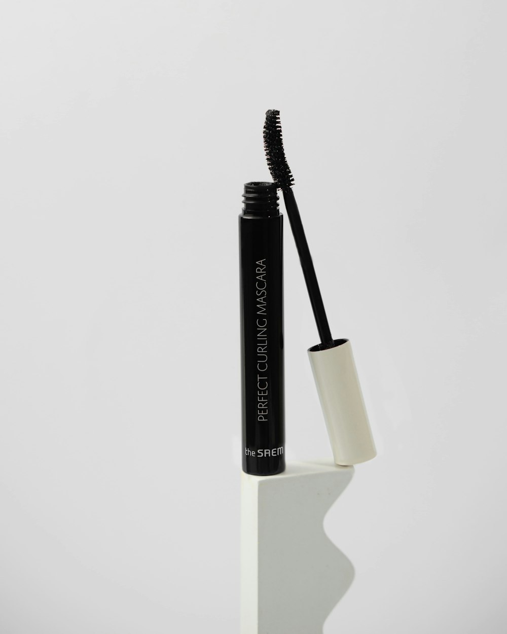 a black mascara sitting on top of a white shelf