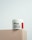 A jar of Naite Thread Neck Cream by MEDI-PEEL rests on a beige platform. The label displays information about the product, which includes enhancing skin elasticity with collagen and peptides. The background is a light, neutral shade which gives a minimalist and clean appearance.