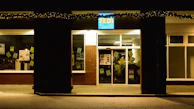 A small business storefront illuminated by bright LED signage at night