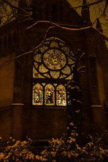 An artistic rendering of the Five of Pentacles card with warm light spilling from a church window onto the snow.