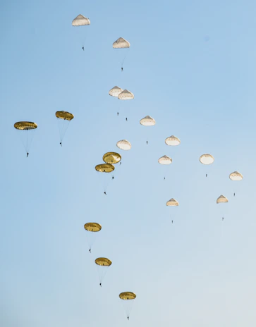 Group of paratroopers in formation mid-air against a clear blue sky.
