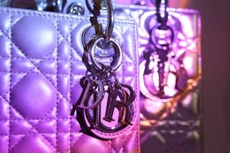 A close-up of a woman’s hand carrying a chic handbag with purple gradient straps.