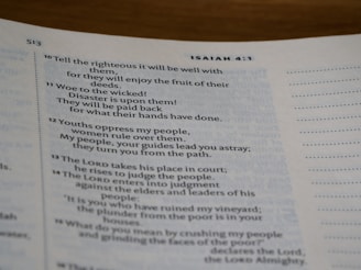 A close-up of an open book displaying text from a chapter, potentially from a religious scripture common in bibles. The visible text discusses themes of righteousness, wickedness, and justice.