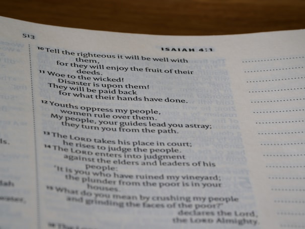 A close-up of an open book displaying text from a chapter, potentially from a religious scripture common in bibles. The visible text discusses themes of righteousness, wickedness, and justice.